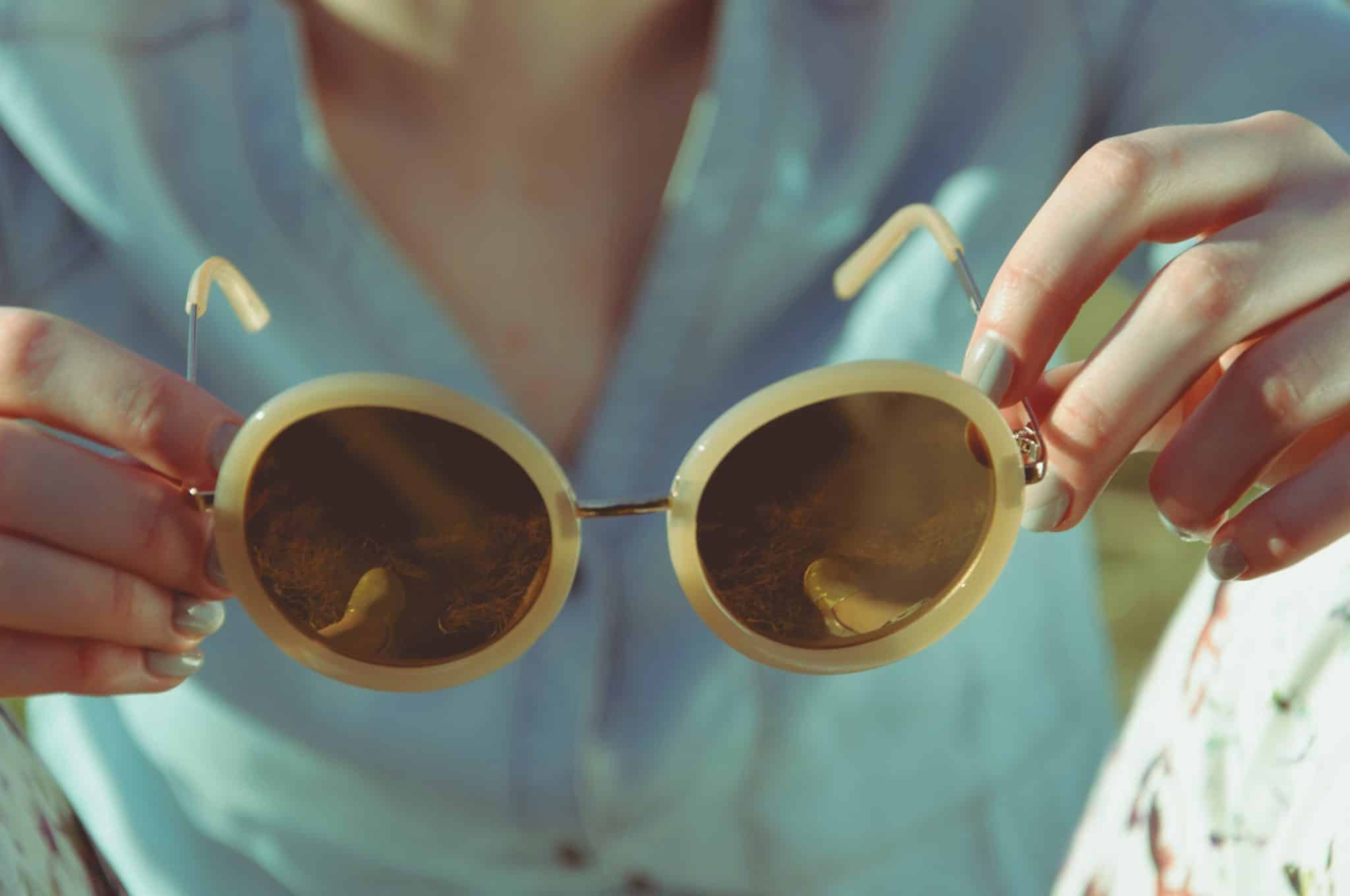 Image décorative - Femme tenant dans ses mains une paire de lunette de soleil