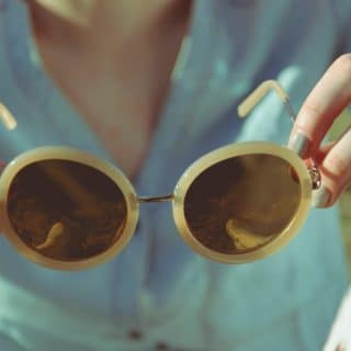 Image décorative - Femme tenant dans ses mains une paire de lunette de soleil